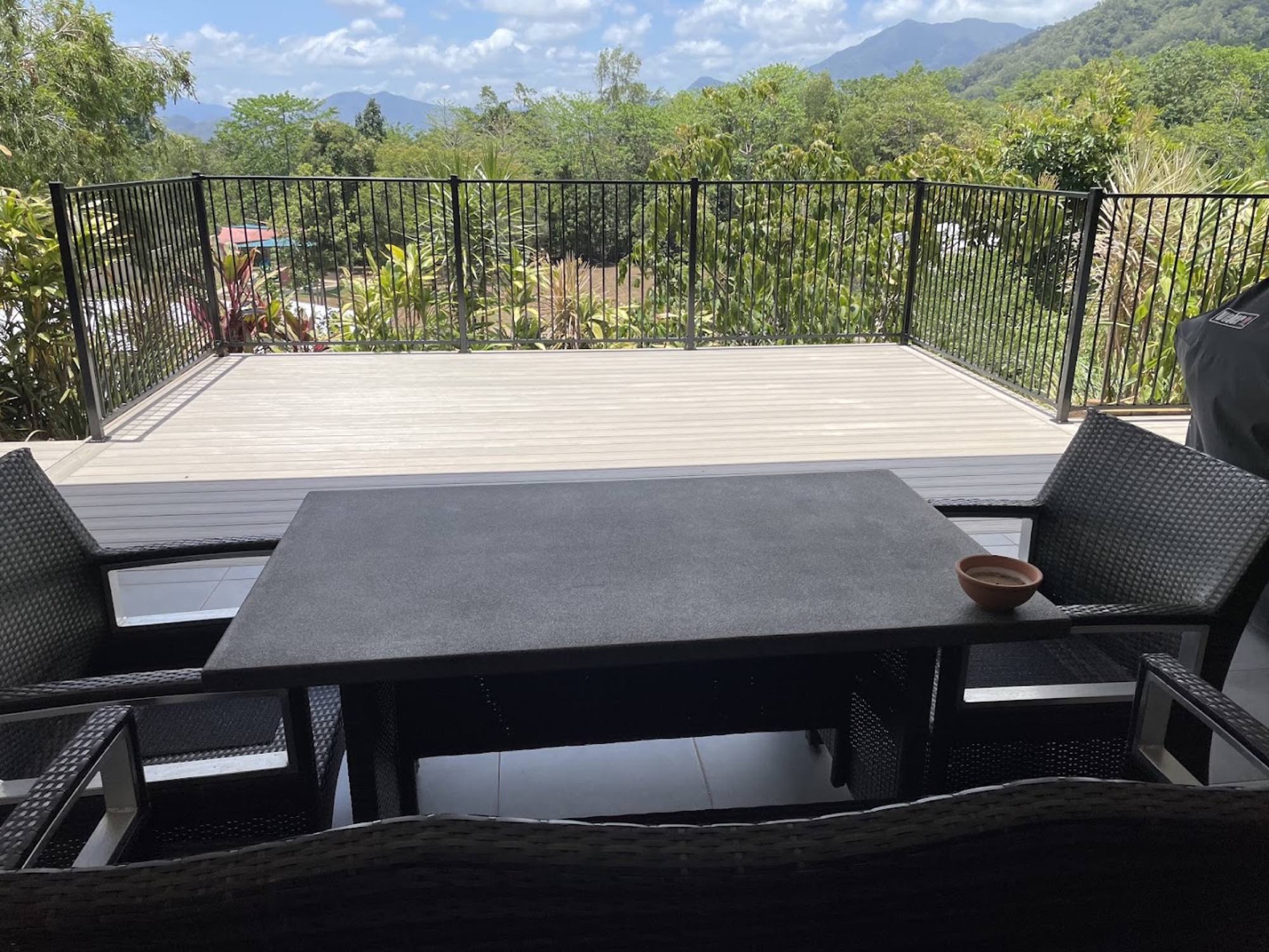 A composite deck with black balustrade looking out over rainforest ridges