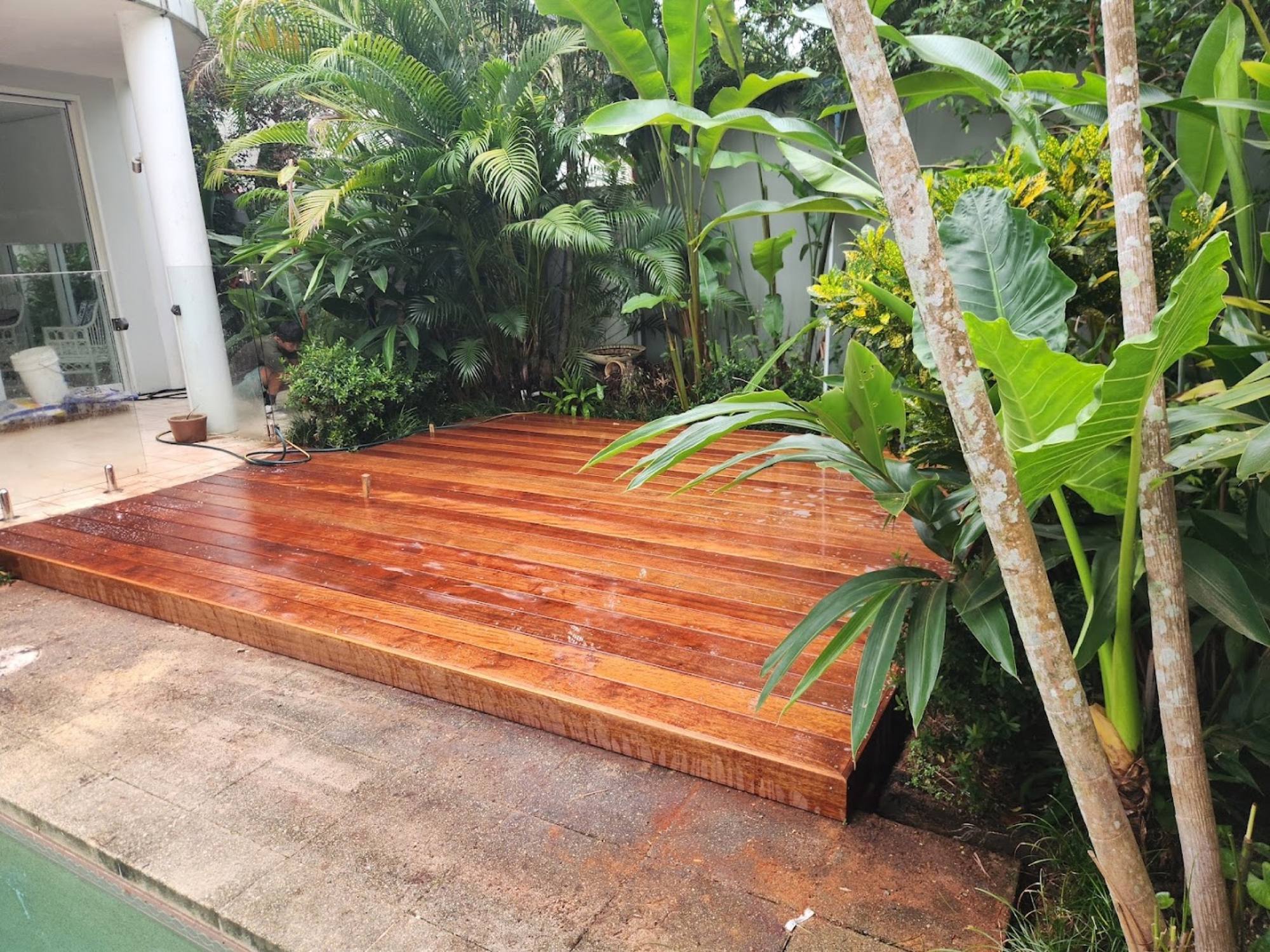 A freshly oiled hardwood deck laid beside a tropical garden