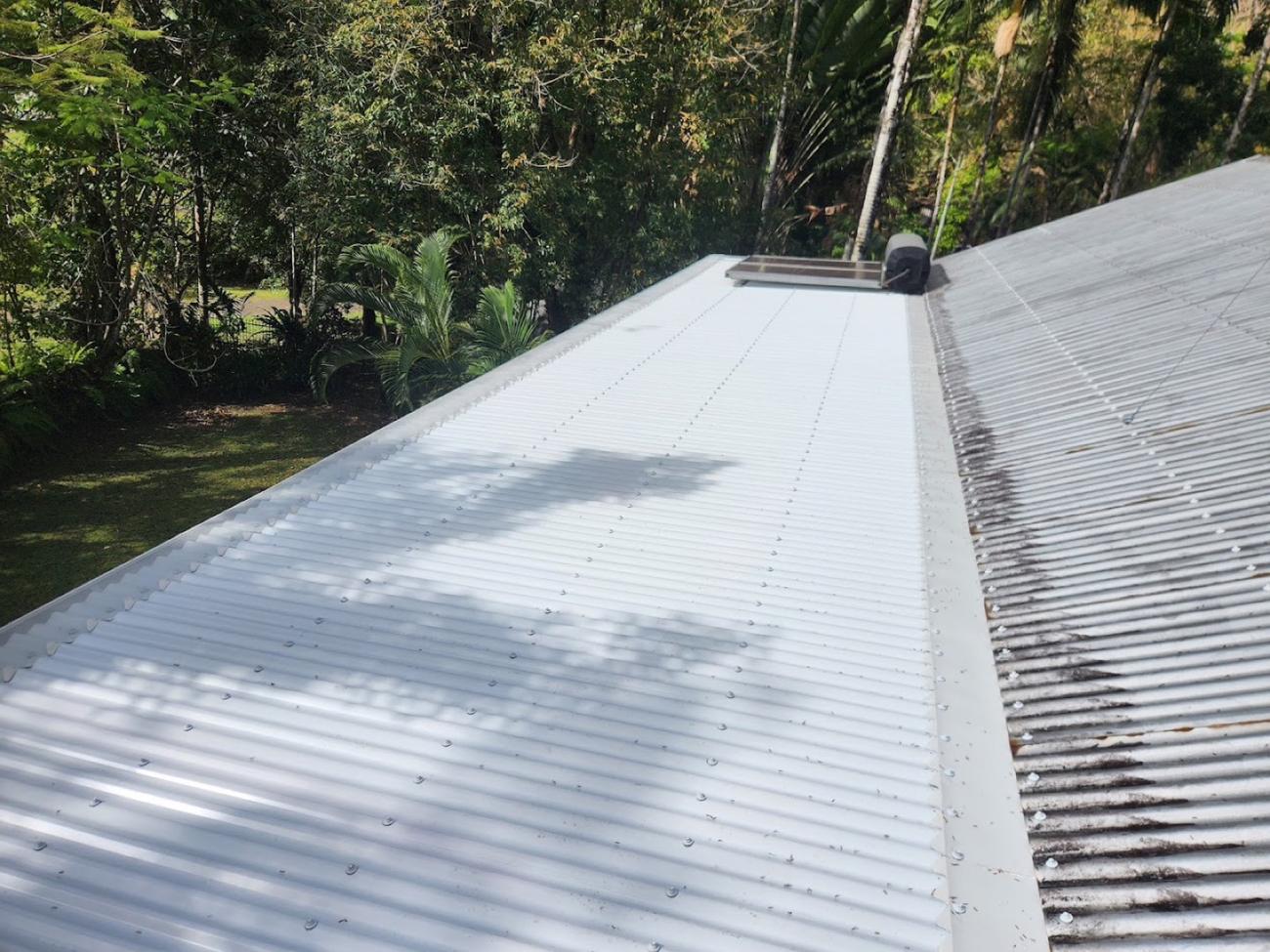 A section of new white roof sheeting laid beside older weathered corrugated iron