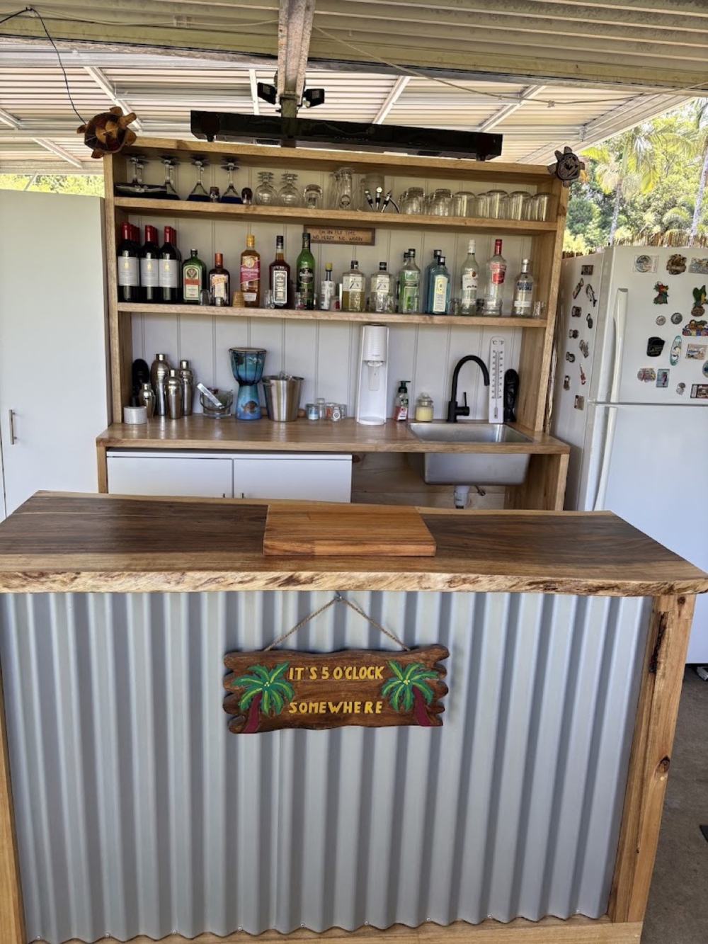 An outdoor bar with a timber top and a corrugated iron front under a patio roof