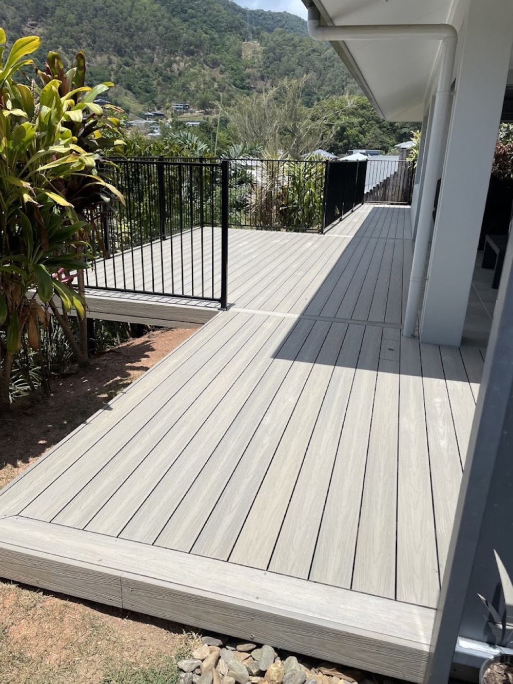A composite deck wrapping the corner of a house above a garden bed