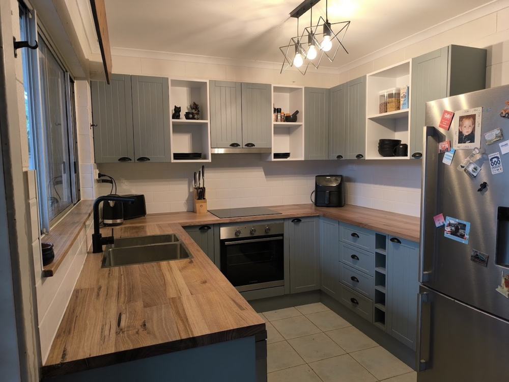 A renovated kitchen with sage cabinetry and timber benchtops