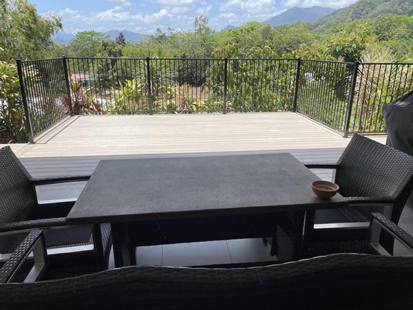 A composite deck with a black balustrade and an outdoor table, mountains beyond