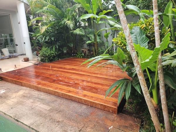 A freshly oiled hardwood deck laid beside a tropical garden