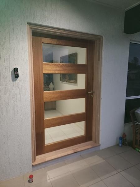 A tall timber entry door with horizontal glass panels set in a rendered wall