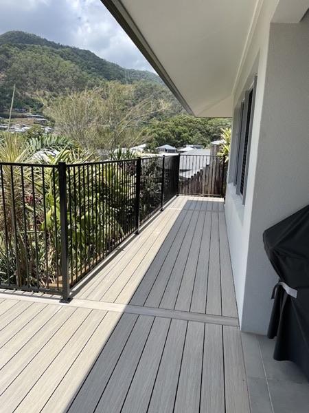 A composite deck on a balcony with a black balustrade and mountain views beyond