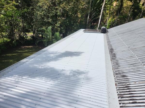 A section of new white roof sheeting laid beside older weathered corrugated iron