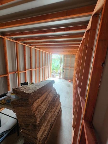 The inside of a shipping container fitted out with timber wall framing and stacked insulation batts