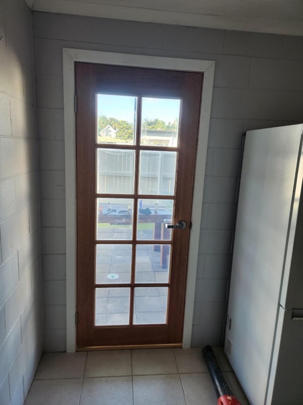 A timber French door with glazed panes fitted into a block wall