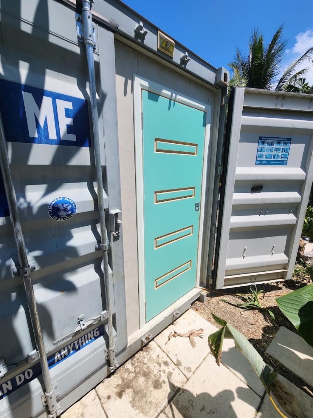 A painted door and frame fitted into the side of a shipping container
